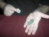 magician holds two coins in his left palm and two coins in between his right thumb and forefinger