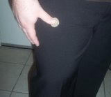 Magician holds coin against leg with right thumb