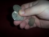 Magician holds four coins in between his right thumb and forefinger 