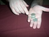 magician holds three coins in his right hand and one in his left