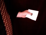 magician holds coin against paper