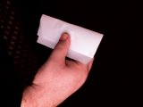 magician folds top of paper down over coin