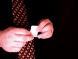 magician folds bottom of paper over coin